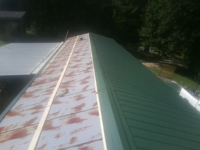 Old rusted panels beside newly installed green metal roofing — Wind Damage Roof Repair by Roofing Brothers in Jensen Beach