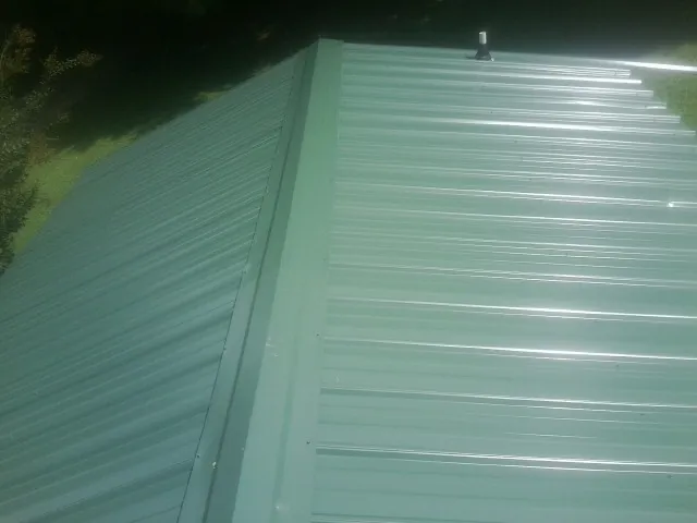 New green metal panels meeting at the ridge of a roof — Flat Roof Repair work by our crew in Jensen Beach