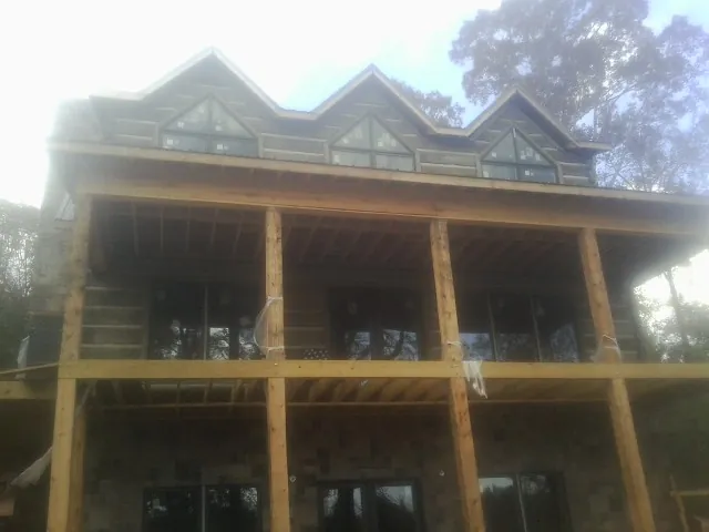 Dormers and porch framing on a large log home under construction — Roof Coating work by our crew in Jensen Beach