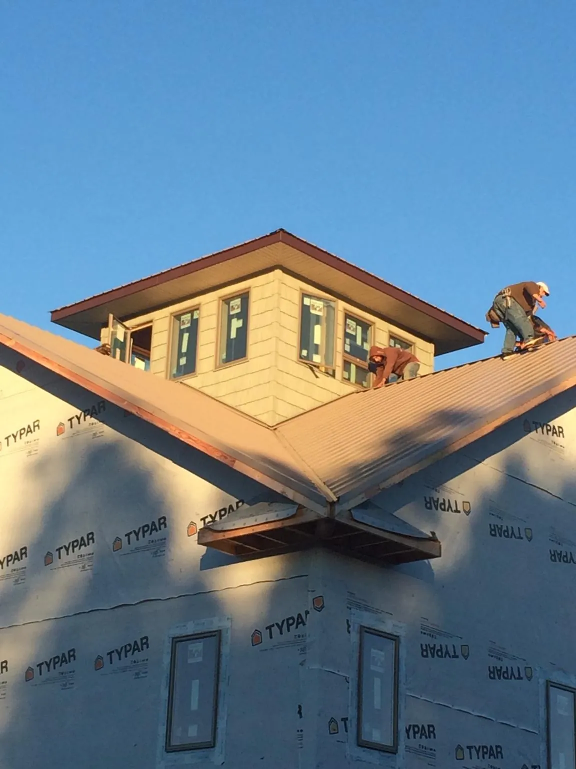 Roofers working around a rooftop cupola on a new metal roof at sunset — Roof Waterproofing in Jensen Beach by Roofing Brothers